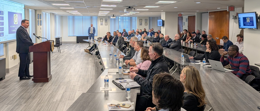 Group of attendees listening to a person addressing the group