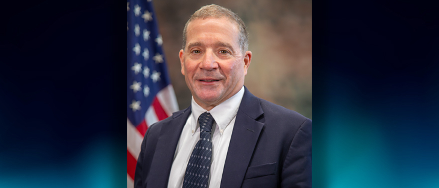 Image of Mr. Lobuglio posing in front of an American flag